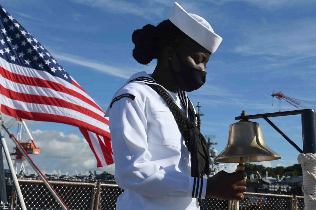 A sailor rings a bell on board a military ship.
