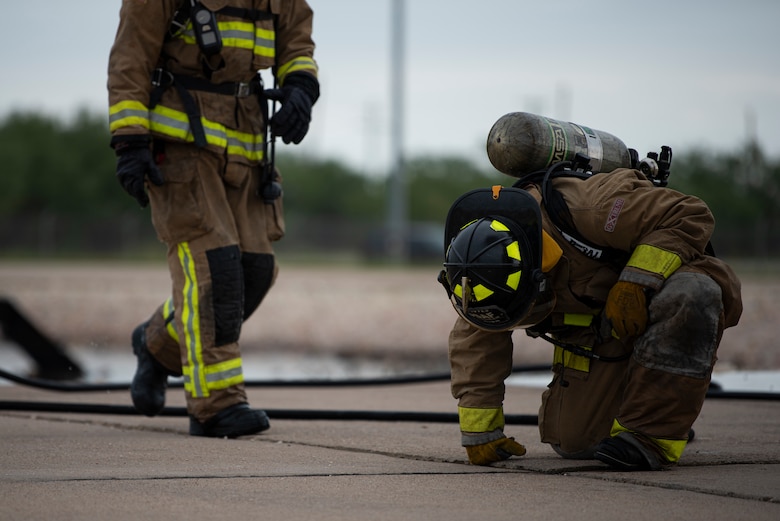 Senior Airman Thomas Rush, 7th Civil Engineer Squadron firefighter, kneels after extinguishing a fire on an aircraft fire trainer at Dyess Air Force Base, Texas, Sept. 15, 2020. The 7th CES firefighters wear equipment that weighs approximately 45 pounds while extinguishing fires that can reach up to 1,000 degrees. (U.S. Air Force photo by Airman 1st Class Colin Hollowell)