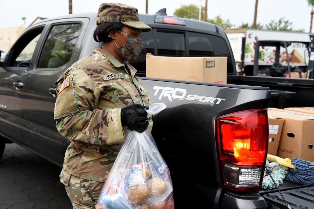 A guardsman wearing a face mask and gloves deliver groceries to a food bank.
