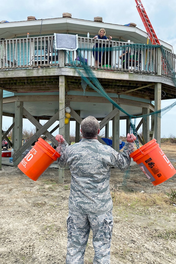 Louisiana Air National Guard Master Sgt. Mark Cusimano, 159th Maintenance Group, offers supplies to a resident in Cameron Parish, La., Sept. 11, 2020. Approximately, 40 Airmen in six teams are working with local government to restore infrastructure and provide much needed supplies to area residents after Hurricane Laura.