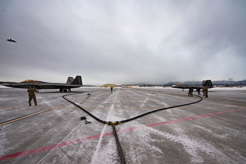 Long hoses run to two fighter jets.