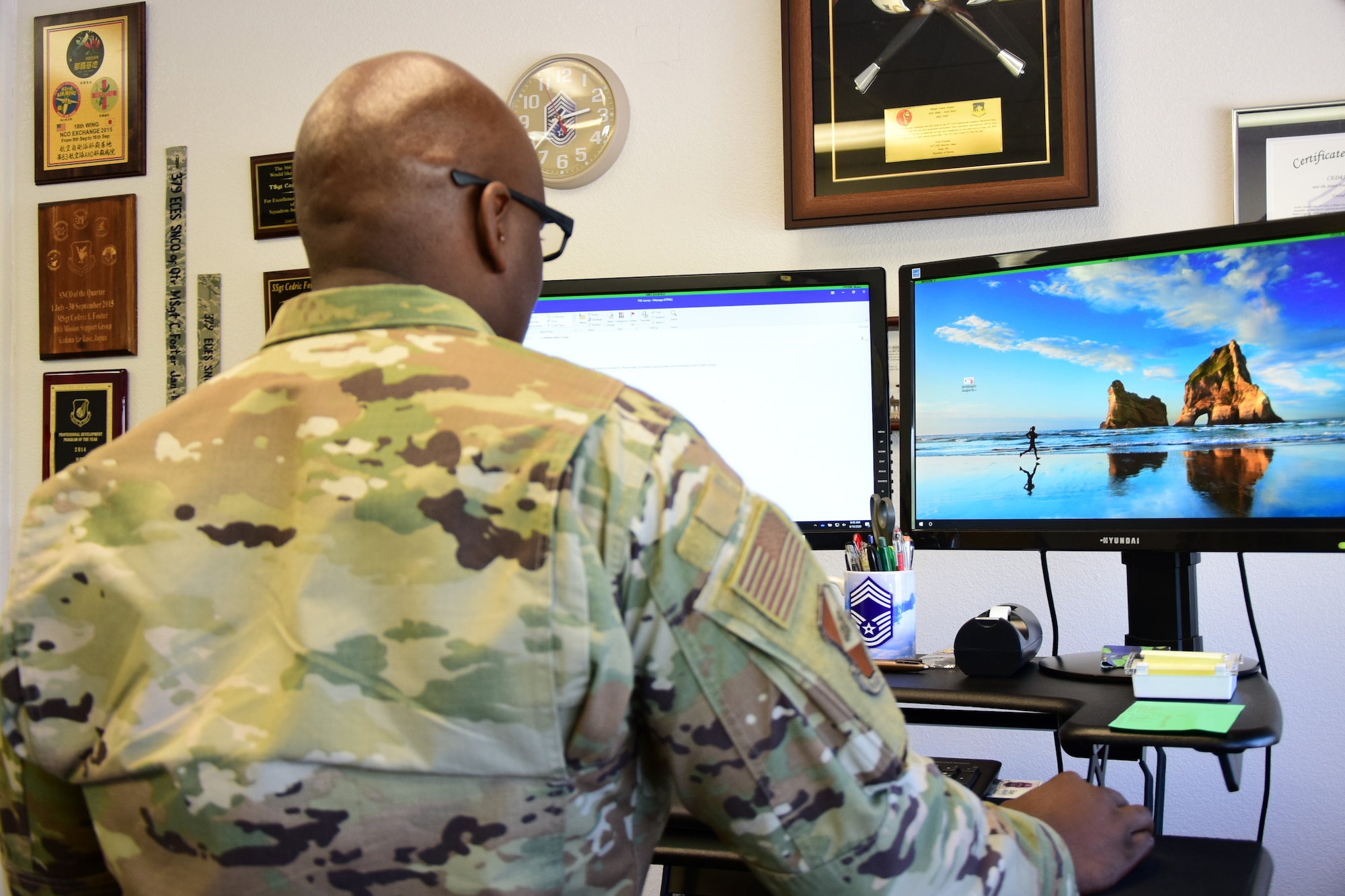 A photo of an Airman standing at his desk.