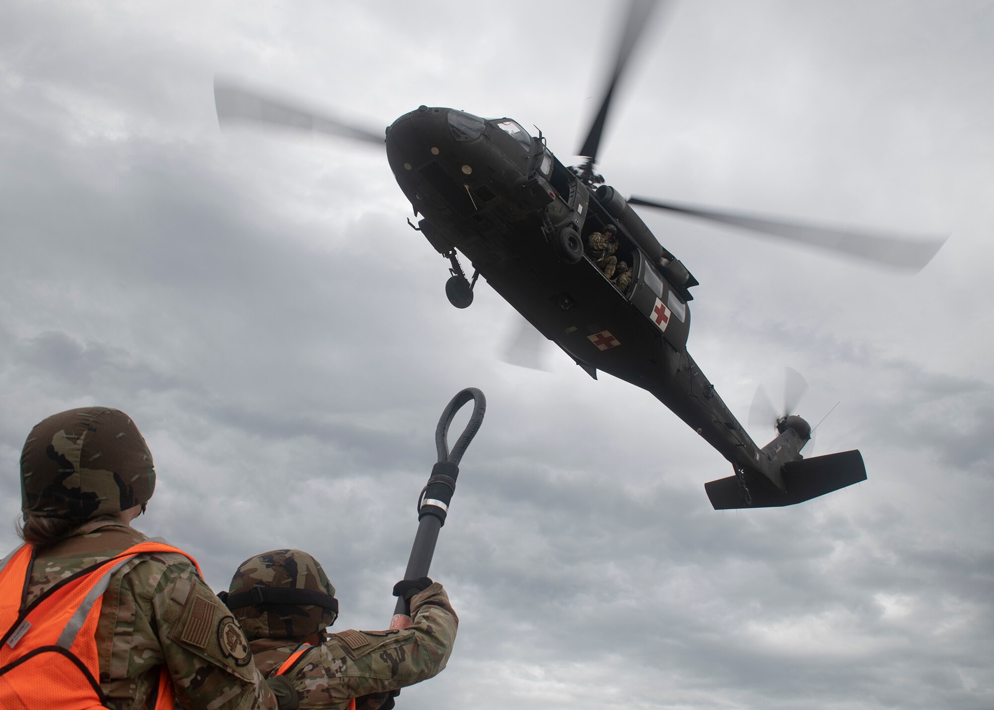 Two Soldiers under helicopter with rigging equipment.