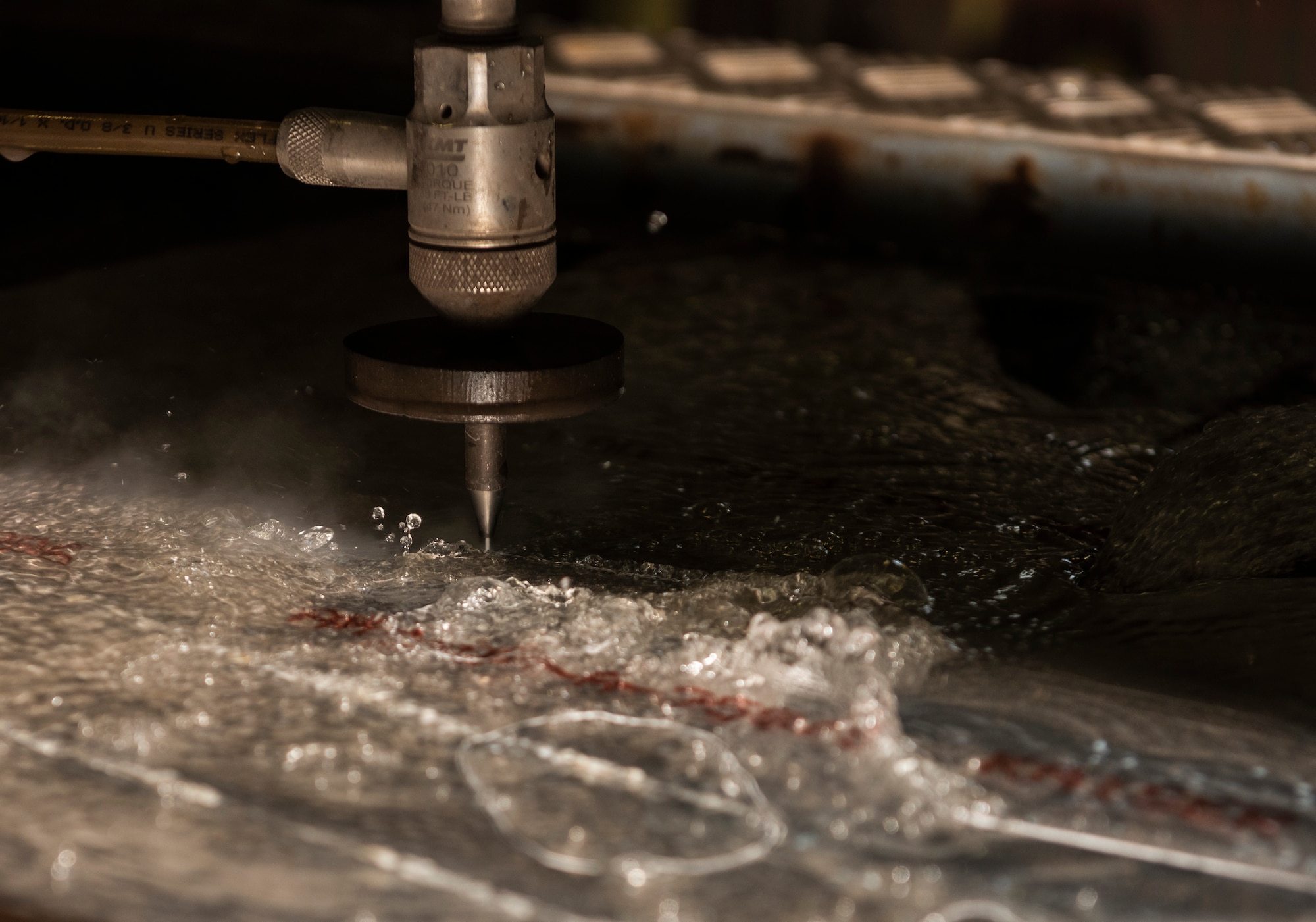 An abrasive water jet machine cuts an aircraft bracket from a sheet of aluminum at Royal Air Force Lakenheath, England, Sept, 15, 2020. The machine uses a combination of water and fine garnet abrasive material, forced through a 0.015” mixing tube at a pressure of 32,000 psi to slice through various metals to create a multitude of aircraft components to keep the 48th Fighter Wings fleet of F-15’s in top flying condition. (U.S. Air Force photo by Airman 1st Class Jessi Monte)