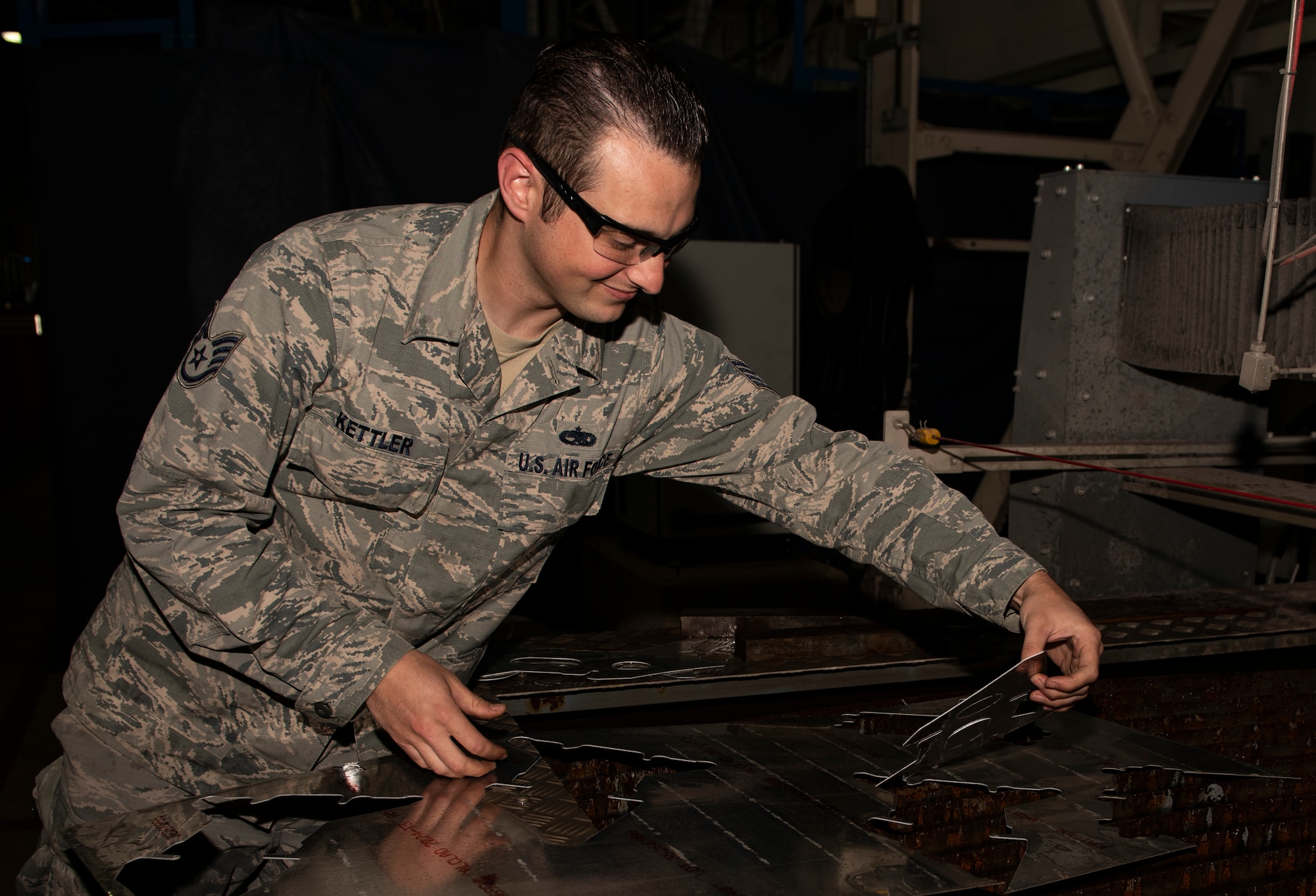 U.S. Air Force Staff Sgt. Derek Kettler, 48th Equipment Maintenance Squadron Fabrication Flight, removes an aircraft bracket from a sheet of aluminum at Royal Air Force Lakenheath, England, Sept. 15, 2020. The Fabrication Flight maintains the structural integrity of aircraft using specialized tools and equipment to repair damage and fabricate replacement parts, ensuring the 48th Fighter Wing remains a ready and capable force. (U.S. Air Force photo by Airman 1st Class Jessi Monte)