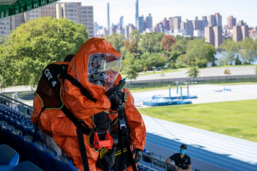 HAZMAT-suited technician searches outdoor stadium.