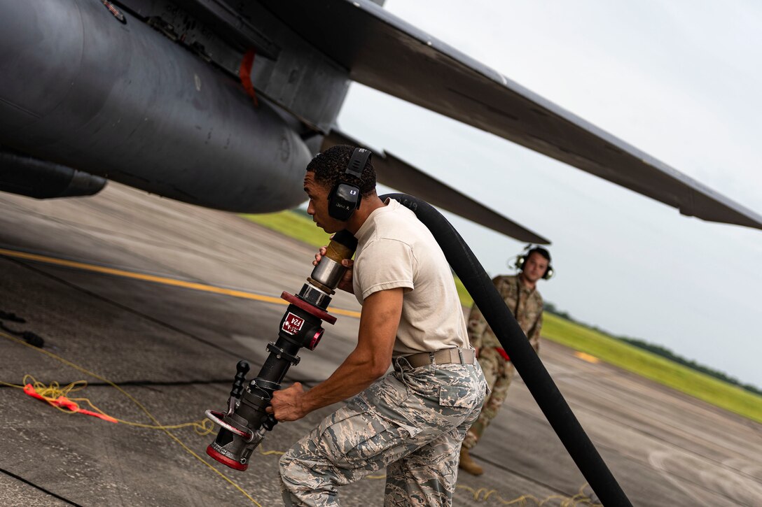 Photo of Airman carrying a refueling nozzle.