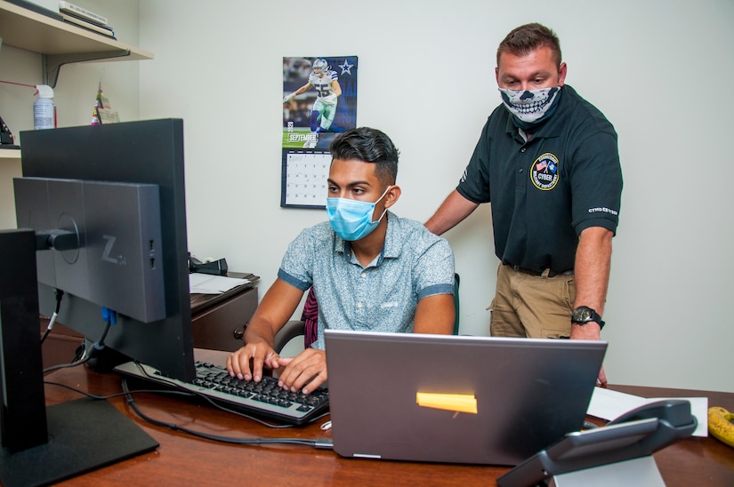 Two men work on computer.