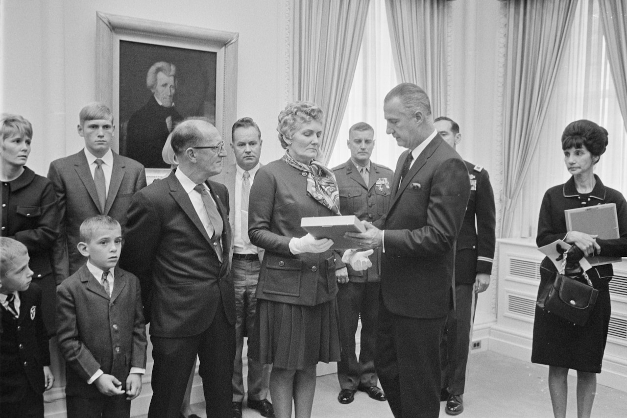 A man hands a plaque to a woman surrounded by her family.