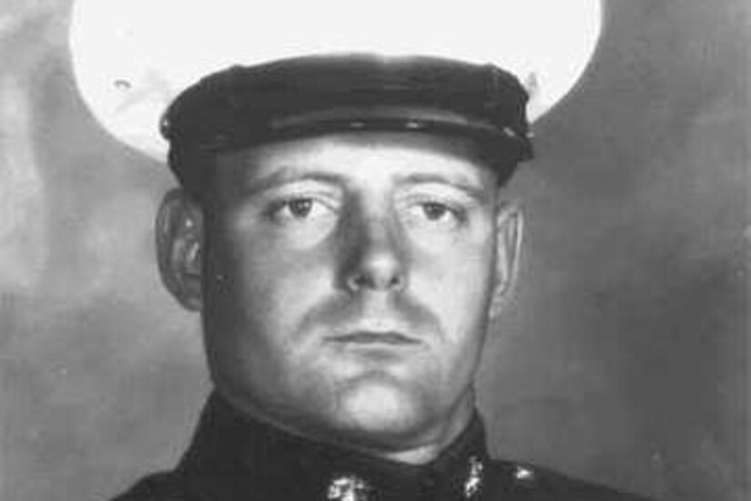 A man in uniform and cap looks forward.