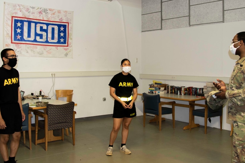 Soldiers wearing face masks ask another soldier a question.