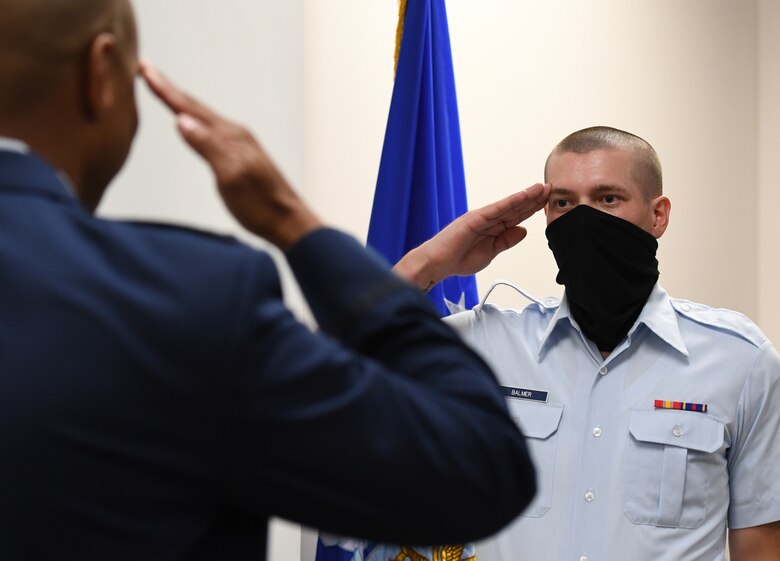 U.S. Air Force Airman Joshua Balmer, 737th Training Group basic military training graduate and son of fallen Air Force Office of Special Investigations Special Agent Ryan Balmer, salutes Special Agent Shannon Robinson, AFOSI Detachment 407 commander, during a presentation ceremony inside the Levitow Training Support Facility at Keesler Air Force Base, Mississippi, Sept. 11, 2020. Balmer was presented mementos by the detachment following his graduation from BMT. (U.S. Air Force photo by Kemberly Groue)