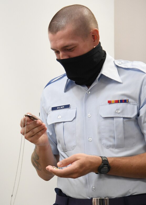 U.S. Air Force Airman Joshua Balmer, 737th Training Group basic military training graduate, looks at a memento during a presentation ceremony inside the Levitow Training Support Facility at Keesler Air Force Base, Mississippi, Sept. 11, 2020. Balmer, son of fallen Air Force Office of Special Investigations Special Agent Ryan Balmer, was presented mementos by AFOSI Detachment 407 following his graduation from BMT. (U.S. Air Force photo by Kemberly Groue)