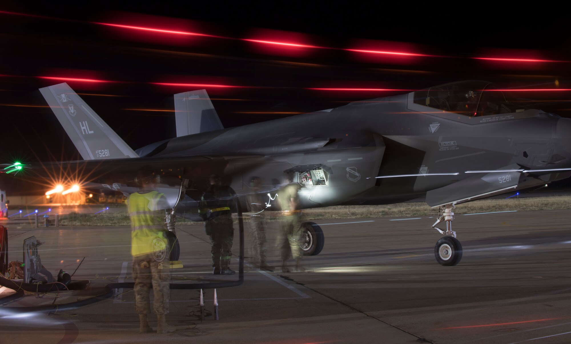 A slow shutter speed captures Airmen conducting a hot pit refueling of an F-35A Lightning II during night operations