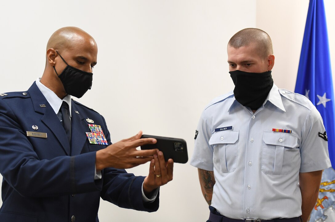 U.S. Air Force Special Agent Shannon Robinson, Air Force Office of Special Investigations Detachment 407 commander, and Airman Joshua Balmer, 737th Training Group basic military training graduate and son of fallen OSI Special Agent Ryan Balmer, watches a zoom greeting during a presentation ceremony inside the Levitow Training Support Facility at Keesler Air Force Base, Mississippi, Sept. 11, 2020. Balmer was presented mementos by the detachment following his graduation from BMT. (U.S. Air Force photo by Kemberly Groue)