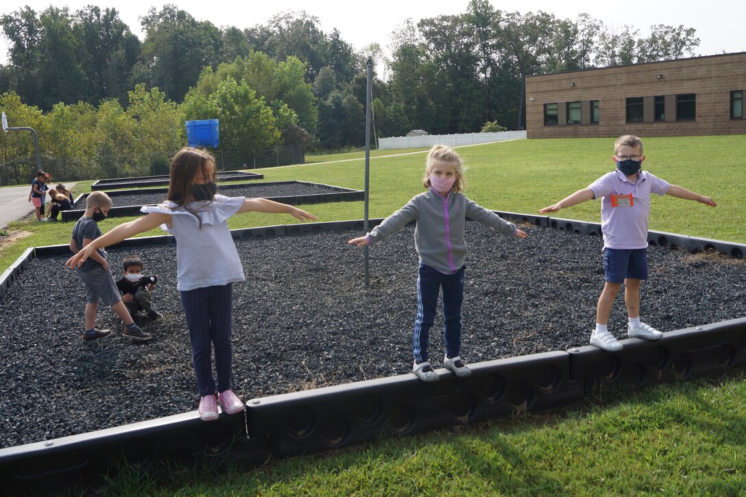 Kids wearing face masks play on a playground.