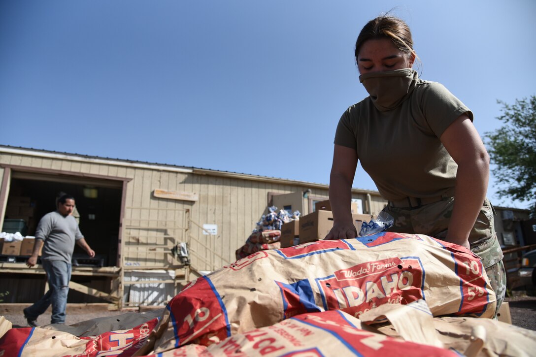 A National Guardsman wearing a face mask moves bags of food for distribution.