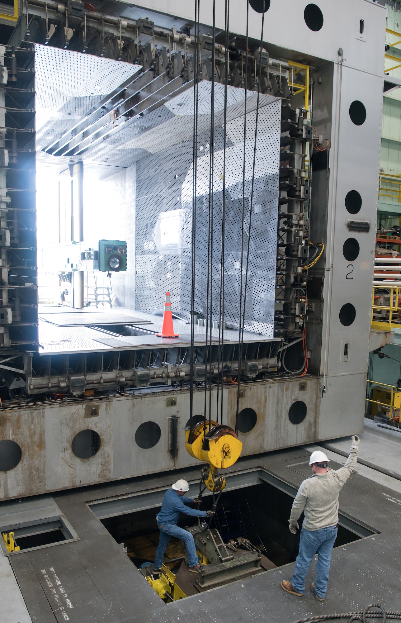 Colby Cox, right, a rigger, directs the crane operator, as Michael Levan, an ironworker, hooks cables to a pitch table to lift it to another location for maintenance, March 16, 2020, in the Model Installation Building at Arnold Air Force Base, Tenn. The pitch table when in use is installed in a test cart and allows the position of an aircraft model to be adjusted. (U.S. Air Force photo by Jill Pickett)