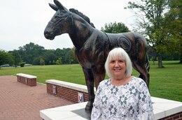 Barbara Wright, assistant to the command group, Special Troops Battalion, 1st Theater Sustainment Command, stands next to the statue of Blackjack outside of Fowler Hall where she works at Fort Knox, Kentucky, Sept. 10, 2020. She is responsible for ensuring  daily operations within the battalion under the two-star command run smoothly by scheduling events and meetings, allowing the STB commander, executive officer, and senior enlisted advisor, freedom to focus their attention on the mission.