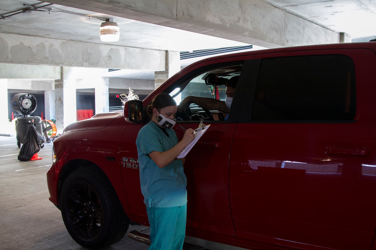 A medical soldier collects patient information at a COVID-19 drive-thru site.