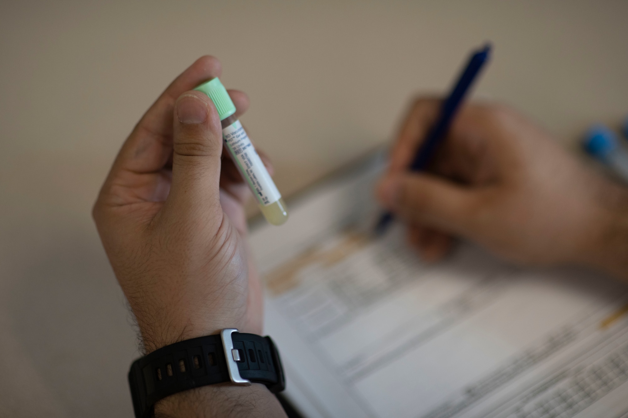 A servicemember holds up a blood work vile as he completes paperwork