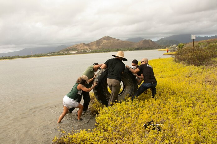 Volunteers push a tire out of the water during a Weed Warriors event aboard Marine Corps Base Hawaii, July 25, 2020. Weed Warriors is a bi-monthly event held by the MCBH environmental staff to remove invasive plant species and debris from the Nu‘upia Ponds wetlands wildlife management area. (U.S. Marine Corps Photo by Lance Cpl. Shane Linder)