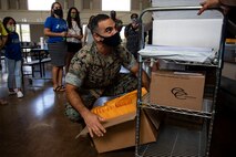 U.S. Marine Corps Col. Speros Koumparakis, commanding officer, Marine Corps Base Hawaii, grabs a box of packets during the Mokapu Elementary School drive-thru pick up, MCBH, July 28, 2020. In prior years, Mokapu Elementary held a “Back to School” event in which families pick up beginning of the school year information and meet their teachers, but this year, for the safety and well-being of students, families, and staff, the school held a drive-thru pick up. (U.S. Marine Corps photo by Lance Cpl. Samantha Sanchez)