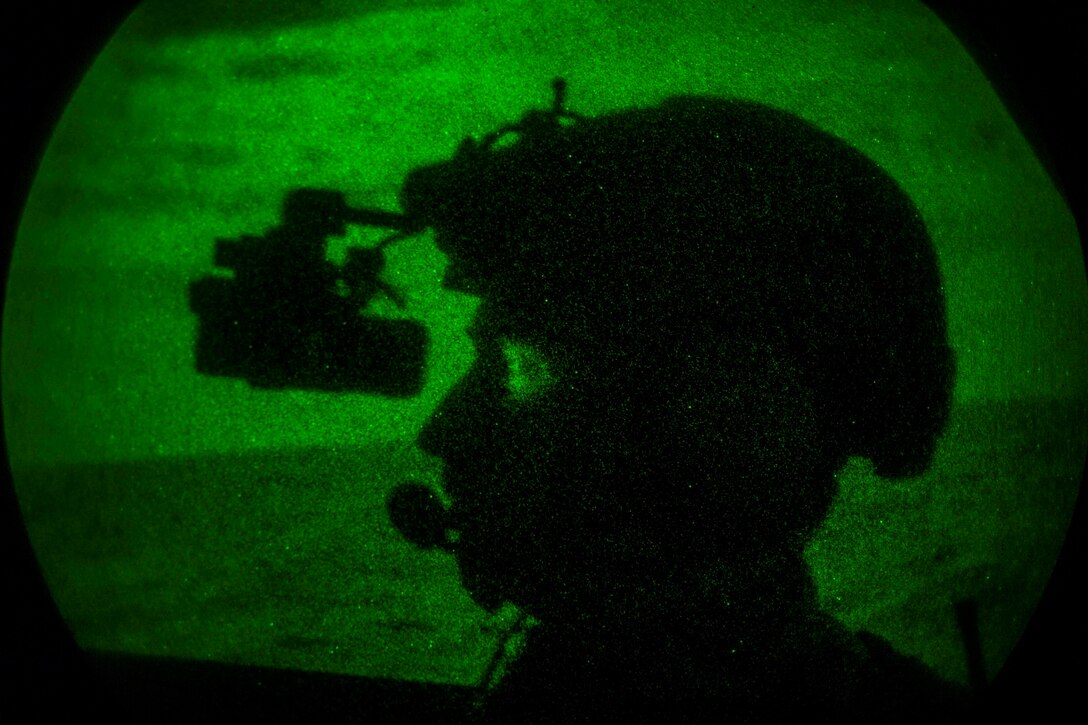 A sailor is illuminated by green light.