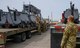 Airmen strap down equipment on flat-bed truck.