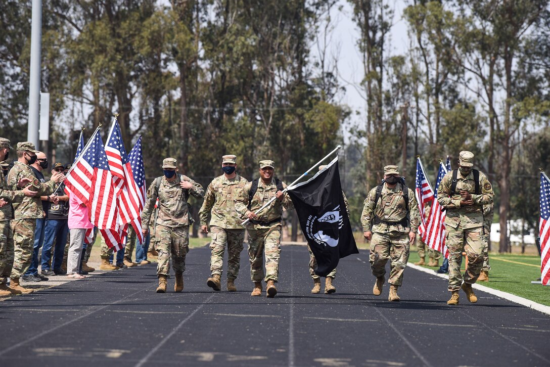 Chief Master Sgt. Daryl Hogan, 30th Space Wing command chief, leads the way, carrying the Prisoner of War and Missing in Action flag, during the first lap around the track at the POW/ MIA Remembrance Ceremony Sept. 17, 2020, at Vandenberg Air Force Base, Calif. The ceremony began with a motorcade, followed by a ceremonial presentation of the POW/ MIA flag and speeches by Vandenberg AFB leadership. After the ceremony, members from across the installation participated in a 24-hour walk or ruck while carrying the POW/ MIA flag, as well as a continuous 24-hour name reading of the past and current POW/MIA members, until the closing ceremony the next day.  (U.S. Air Force photo by Senior Airman Hanah Abercrombie)