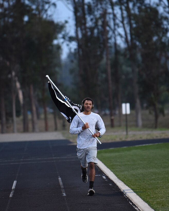 Airman 1st Class Allen Rouse, 30th Civil Engineer Squadron heating, ventilation and air conditioning specialist, runs with the Prisoner of War and Missing in Action flag during the 24- hour POW/MIA remembrance event Sept. 18, 2020, at Vandenberg Air Force Base, Calif. The 24-hour walk or ruck, signifies the countless hours they spent surviving or devising plans to escape. (U.S. Air Force photo by Senior Airman Hanah Abercrombie)