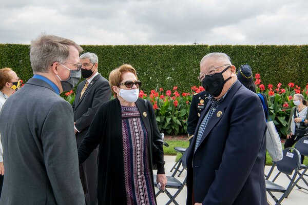 The deputy secretary talks with two attendees at an outdoor ceremony.