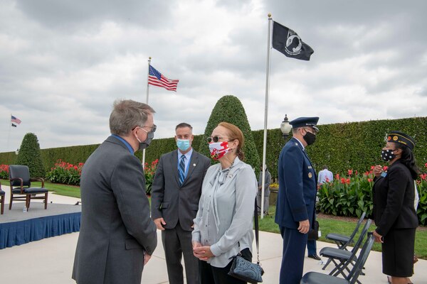 The deputy secretary talks with an attendees at an outdoor ceremony.