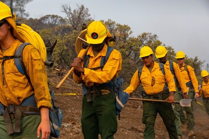 Soldiers with Alpha Battery, 2nd Battalion, 17th Field Artillery Regiment, attached to the 14th Brigade Engineer Battalion, hike up a mountain carrying hoses and equipment to plume the fireline, in order to cool down hotspots, at the August Complex wildland fire Sept. 13, 2020, in Mendocino National Forest.