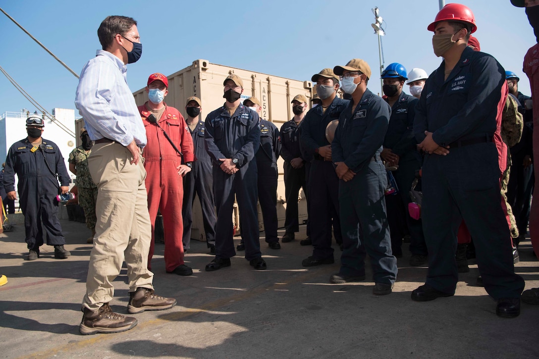 Defense Secretary Dr. Mark T. Esper stand in front of a group of sailors.