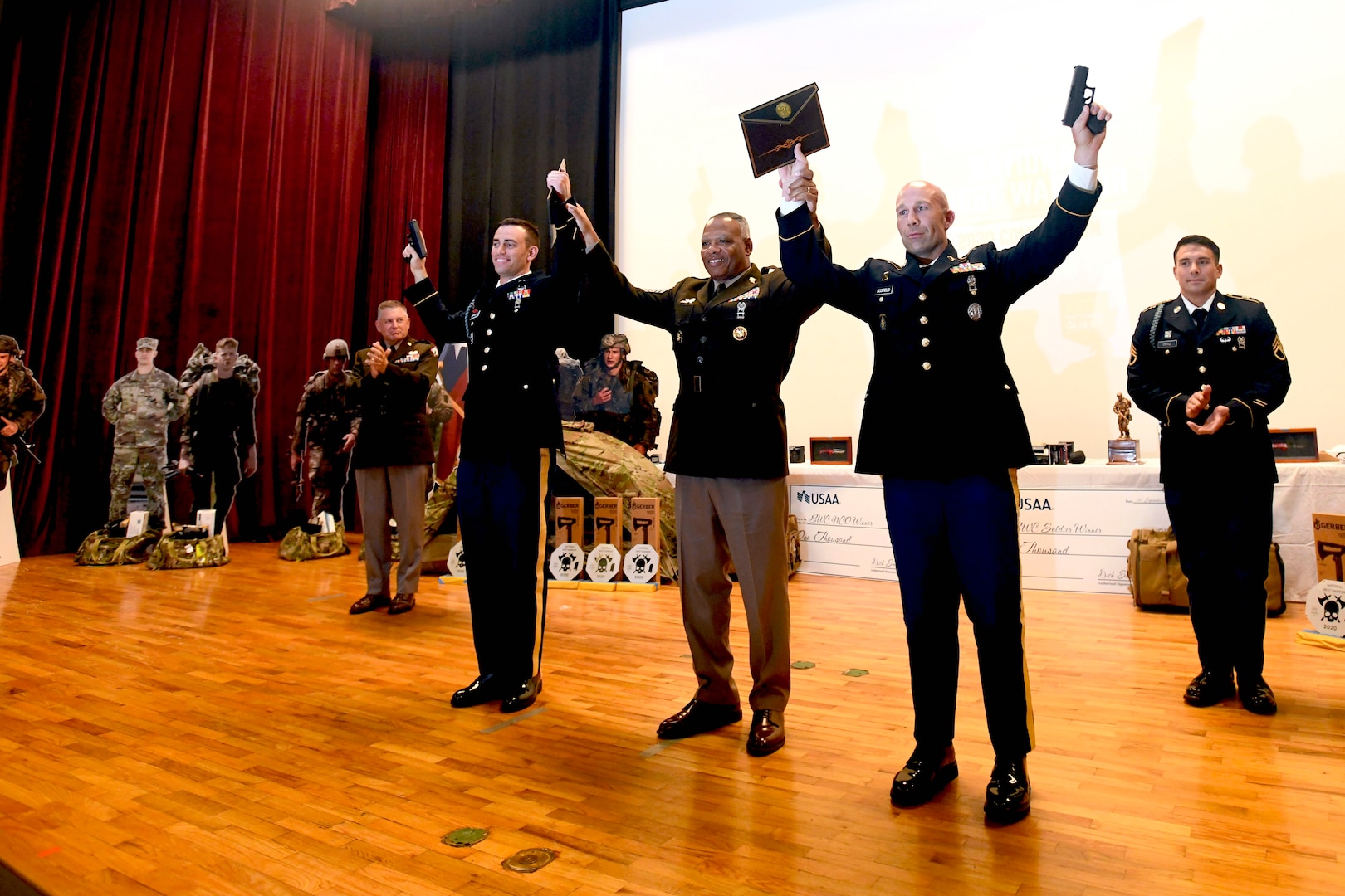 Army Staff Sgt. Mitchell Scofield, front right, a cavalry scout with the Mississippi Army National Guard’s Regional Training Institute, and Cpl. Daniel D’lppolito, an infantryman with the Arizona Army National Guard’s Alpha Company, 1st Battalion, 158th Infantry Regiment, front left, hoist their pistols during the closing ceremony of the Army National Guard’s 2020 Best Warrior Competition at Camp Shelby, Mississippi, Sept. 16. Scofield and D’lppolito earned the titles of Army National Guard Noncommissioned Officer and Soldier of the Year, respectively. Command Sgt. Maj. John F. Sampa, middle, the command sergeant major of the Army National Guard, joins Scofield and D’lppolito in celebrating their new titles. The two Soldiers will go on to compete in the 2020 all-Army Best Warrior Competition, to be held virtually later in the year.