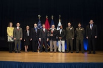 A scientist for the U.S. Naval Research Laboratory was part of a team that received the Navy "Innovation Excellence Acquisition Team of the Year Award" for demonstrated engineering ingenuity in developing a repair solution for delaminated transparent armor estimated to save the Marine Corps $105 million. Dr. Marriner Merrill, NRL researcher (2nd from left) served as a technical lead for this effort, and many others affiliated with NRL also contributed, including Dr. James P. Thomas, William Pogue, Christopher Kindle, Michael Doherty, and Dr. G. T. Pham. The Honorable James F. Geurts, Assistant Secretary of the Navy for Research, Development, and Acquisition, far right, and Ms. Jeanette Evans-Morgis, Deputy to the Commander, Marine Corps Systems Command (MCSC), far left, presented the award to the team, including: (l-r) Dr. Merrill; Ms. Krista Francom, MCSC; Mr. Tom Stevenson, MCSC; Mr. William “Scott” Story, MCSC; Mr. John Rooney, formerly MCSC; Mr. Maurice Johnson, MCSC; Maj. Christopher Kiely, USMC; Maj. Thitipan Durasavin, USMC. Not pictured, Mr. Mark Totten, Marine Corps Syscom. (Department of the Navy)