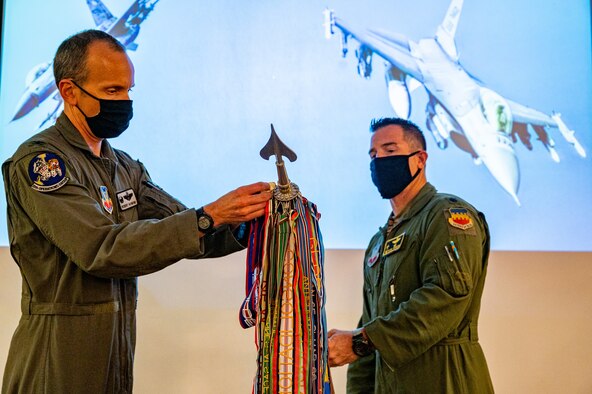 A photo of two Airmen holding a guidon flag.