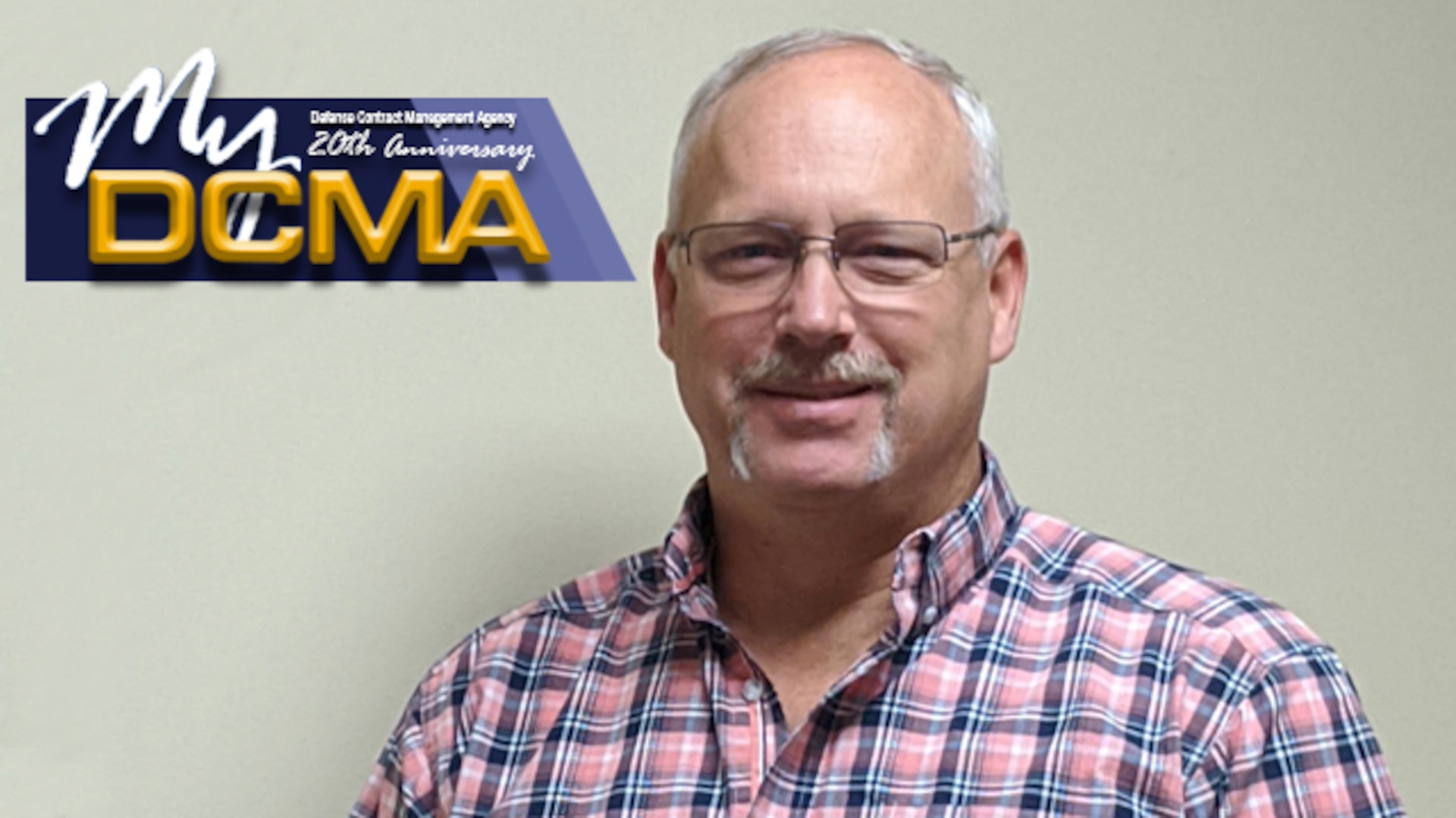 Man wearing striped shirt stands against a wall with the My DCMA logo placed in the upper left portion of the photo