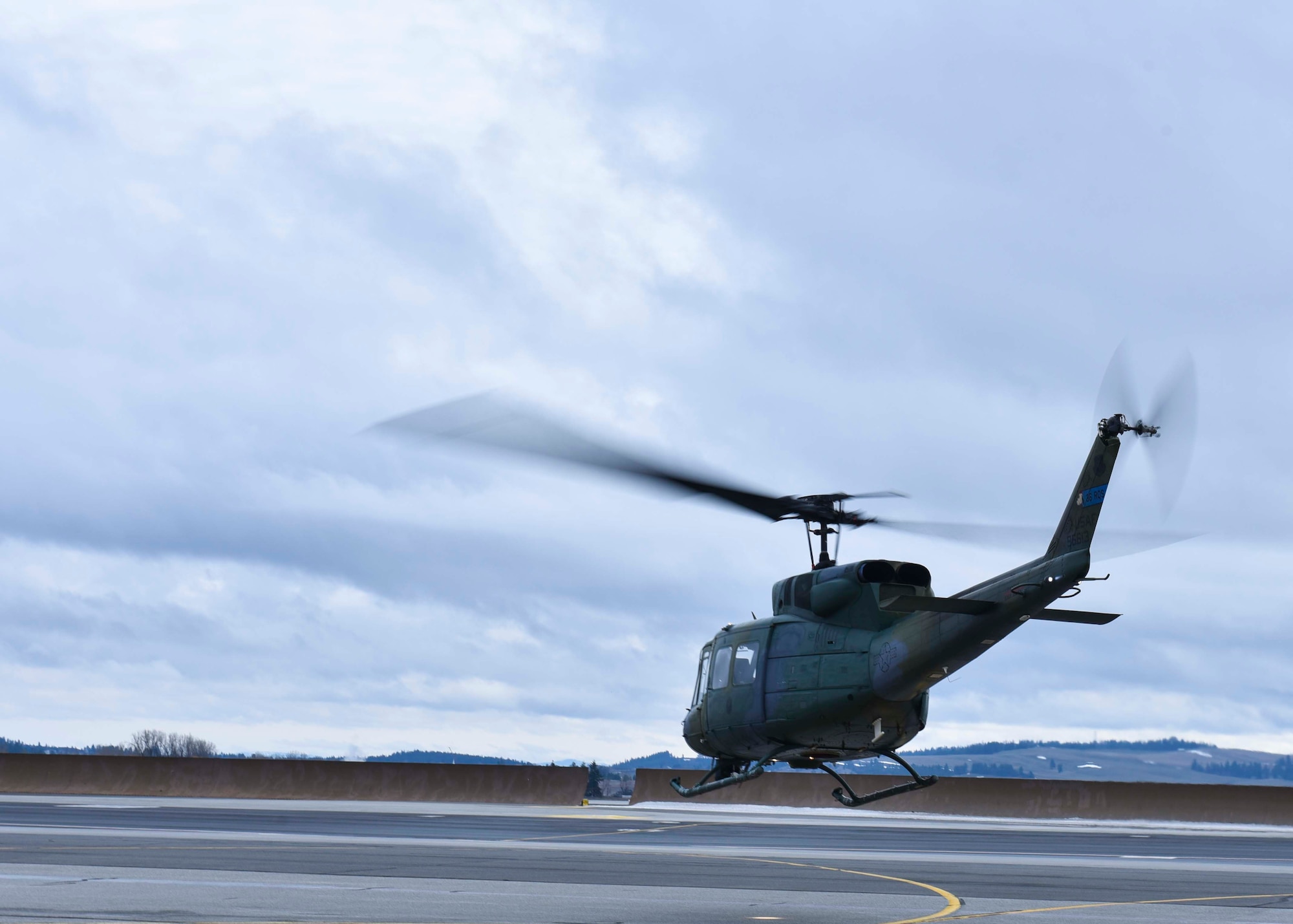 Pilots from the 36th Rescue Squadron fly a Bell UH-1N Iroquois helicopter to students from the Survival, Evasion, Resistance and Escape school preforming field training at Fairchild Air Force Base, Washington, Jan. 30, 2020. Students from the SERE school were hoisted into the helicopter as part of a evading enemy territory simulation. (U.S. Air Force photo by Airman 1st Class Kiaundra Miller)