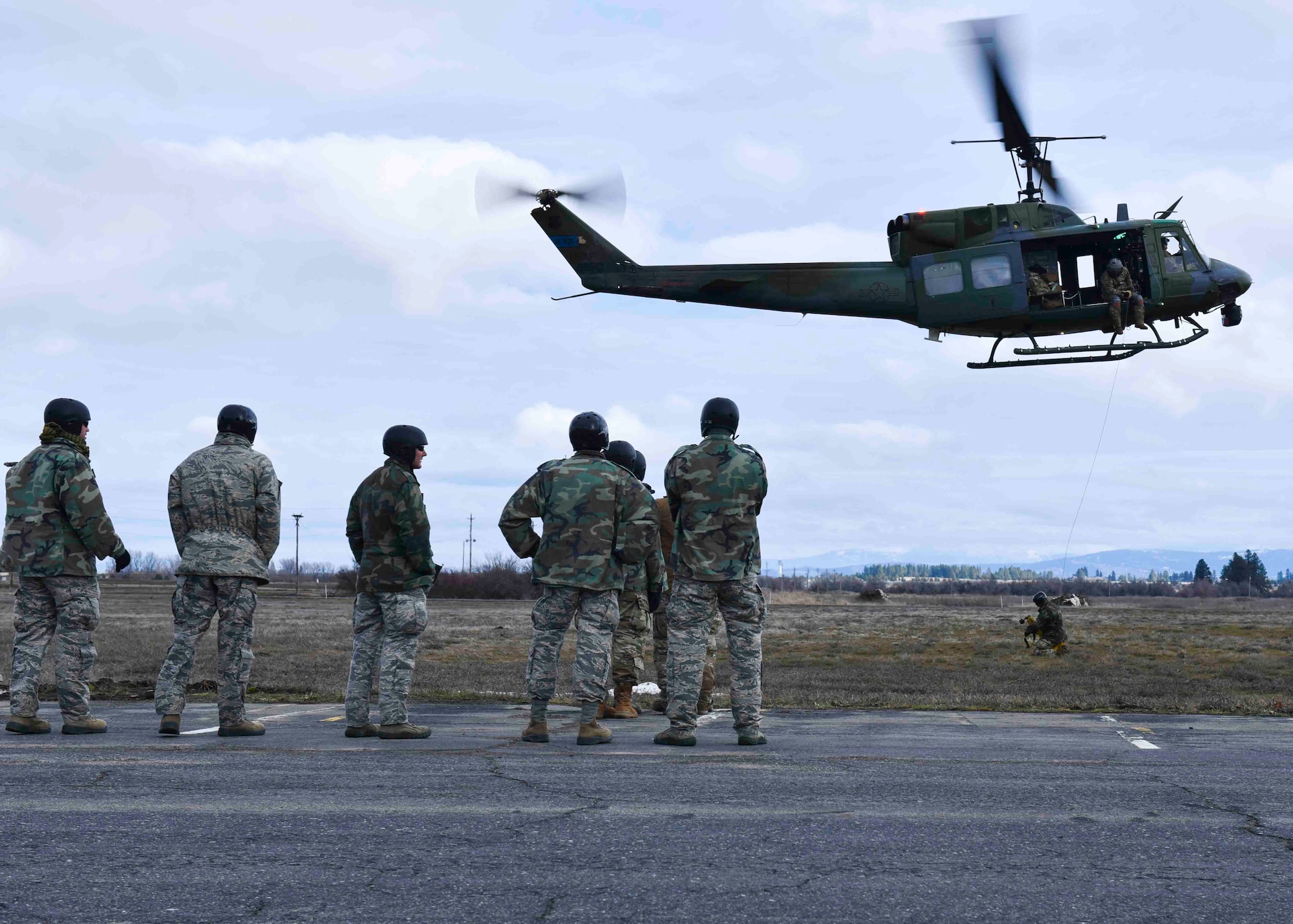 Students from the Survival, Evasion, Resistance and Escape school watch as their fellow student is hoisted into a Bell UH-1N Iroquois helicopter as part of training at Fairchild Air Force Base, Washington, Jan 30, 2020. Students from the SERE school go through a 19 day course that includes water training, outdoor survival, and being hoisted into a helicopter. (U.S. Air Force photo by Airman 1st Class Kiaundra Miller)