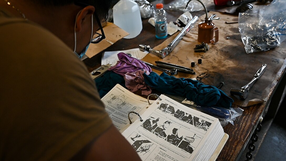 Sailor studies a technical manual during marine engine training.
