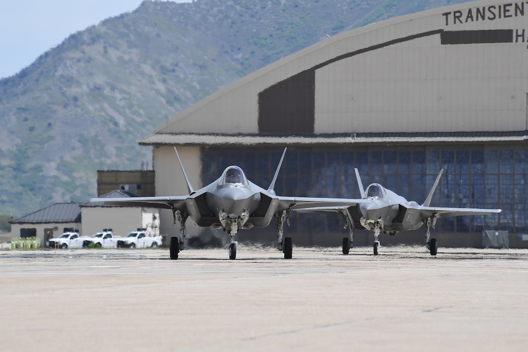 Jets sit in front of a hangar.