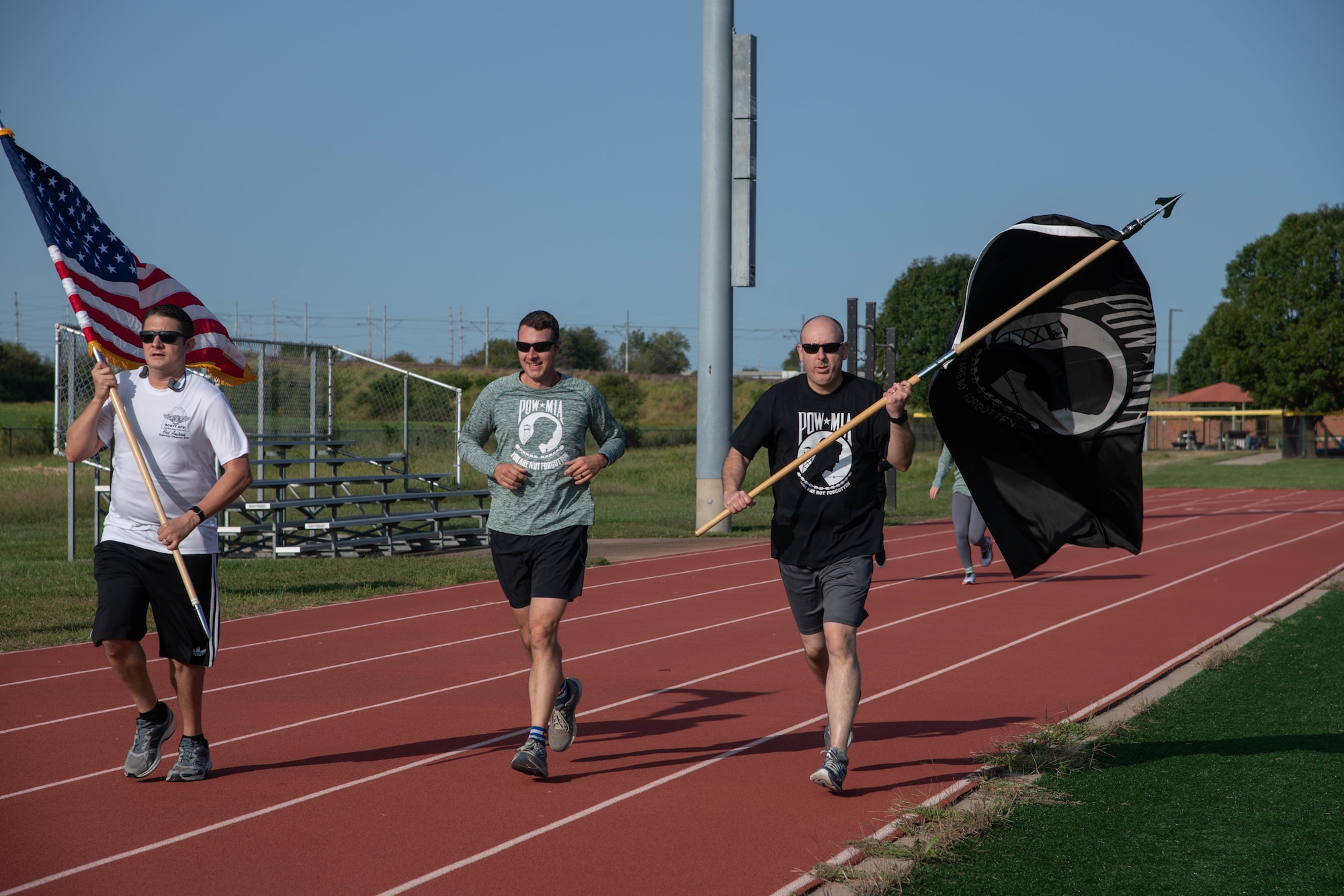 People running on track while holding POW/MIA flag.