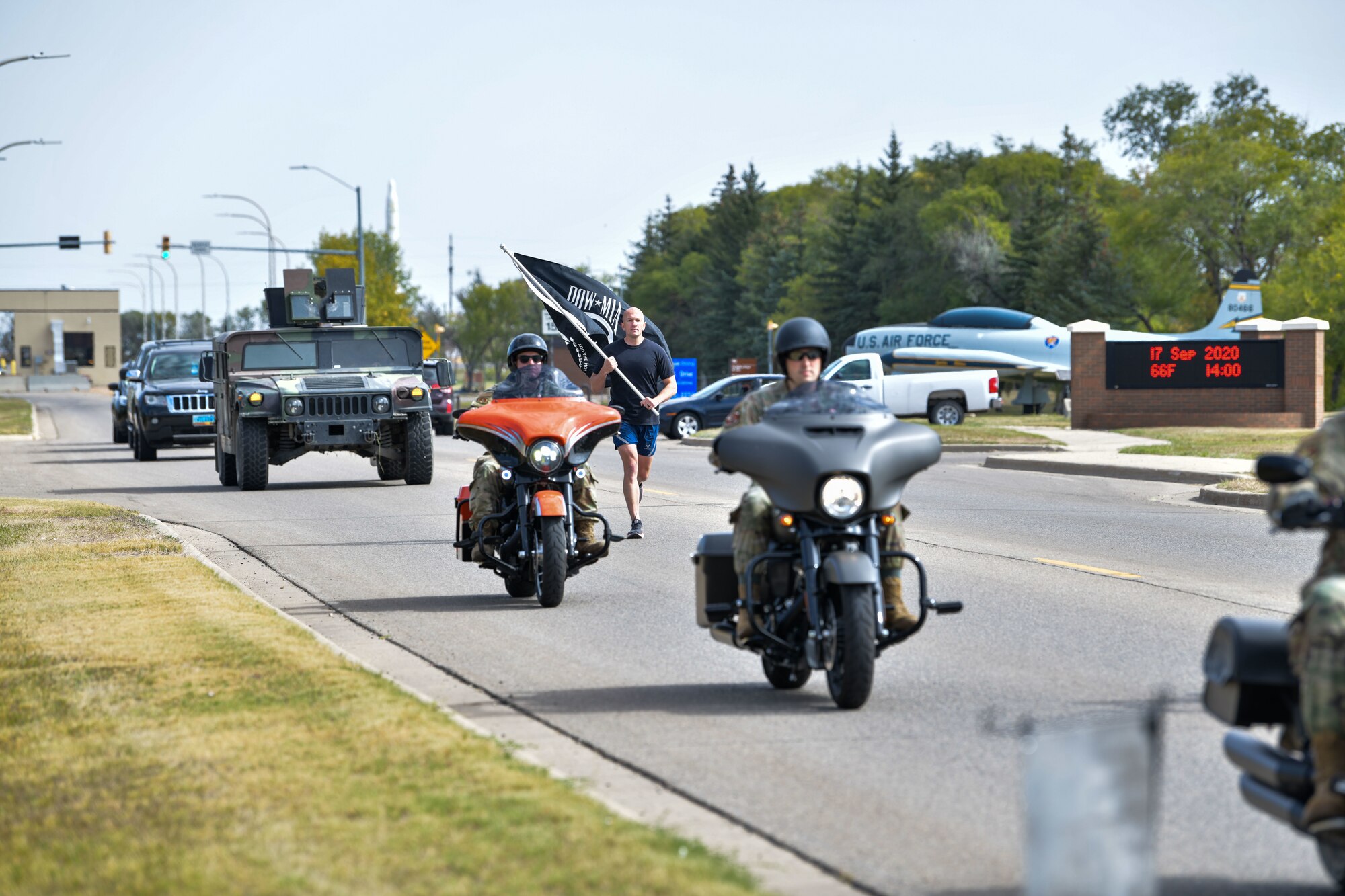 A team Minot Airman runs with the POW/MIA flag as the “Lone Runner” Sep. 17, 2020, at Minot Air Force Base, North Dakota. The run started from the main gate and finished at the base track, the first part of the run consisted of a “Lone Runner” carrying a POW/MIA flag escorted by motorcycles. Upon arrival at the track, names of those who were prisoners of war or missing in action were read as the “Lone Runner” handed the POW/MIA flag to the next volunteer and started the first 30-minute interval of the day. U.S. Air Force photo by Airman First Class Jan K. Valle)