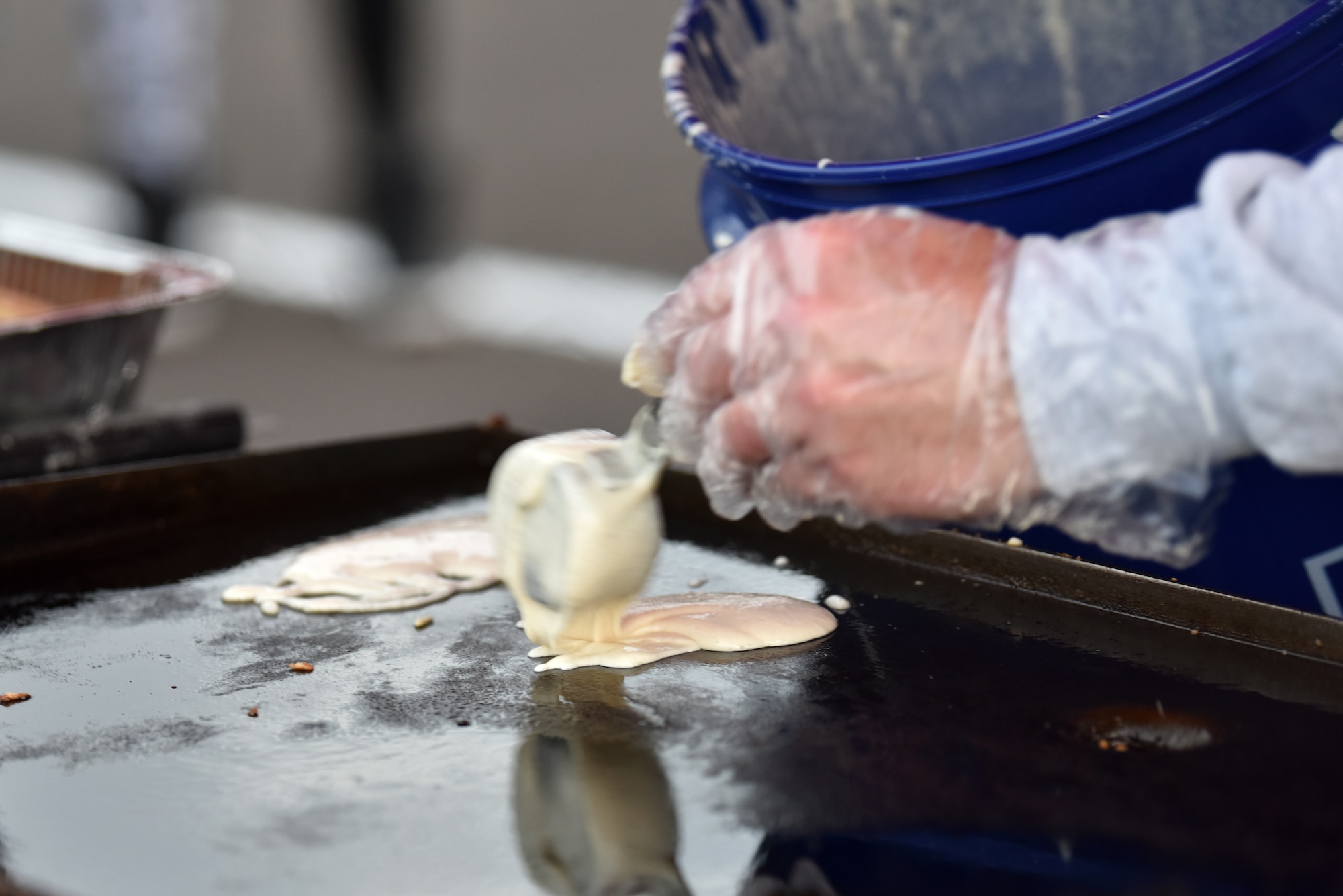A volunteer pours pancake batter onto a griddle in preparation for the pancake breakfast served before and after the Air Force Birthday Celebration held on the Parade Field at Goodfellow Air Force Base, Texas, Sept. 18, 2020. Despite COVID-19 Goodfellow members were able to enjoy events throughout the week celebrating the Air Force’s birthday. (U.S. Air Force photo by Staff Sgt. Seraiah Wolf)