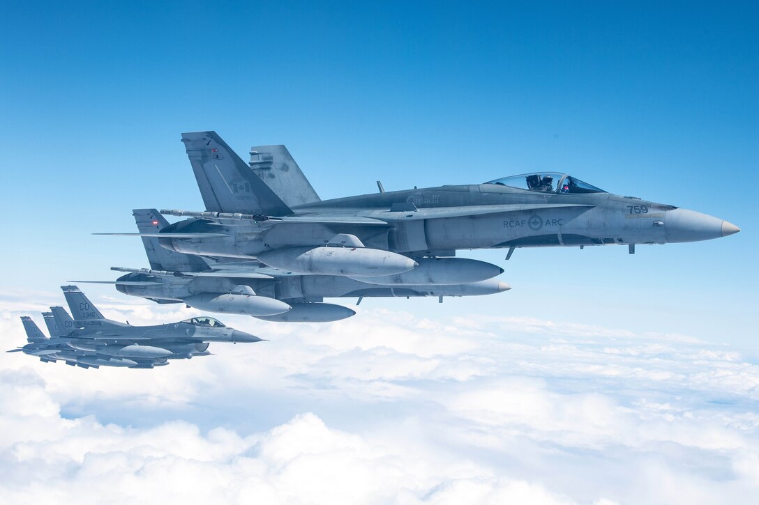 Six aircraft fly above clouds.