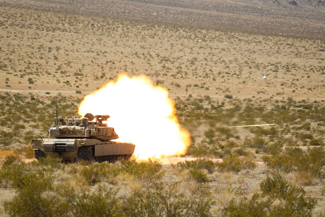 A tank fires a large blast in the middle of a field.