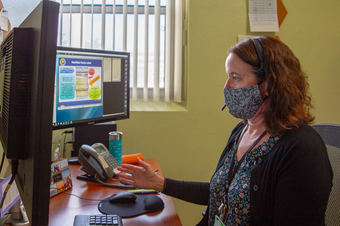 A woman wearing a mask uses computer.