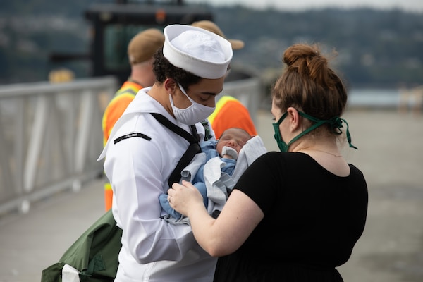 A Sailor assigned to the guided-missile destroyer USS Kidd (DDG 100) meets his newborn child for the first time.